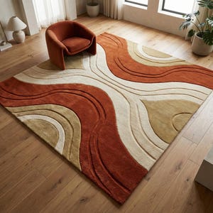 May include: A large, rectangular area rug with a wavy pattern in shades of rust, cream, and beige. The rug is placed on a hardwood floor, and a rust-colored armchair sits on the floor near the rug.
