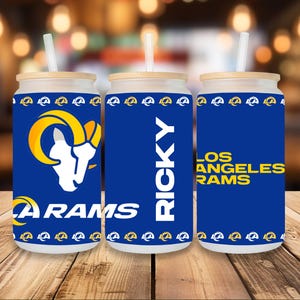 May include: Three blue and yellow insulated tumblers with a Rams logo and the words "Los Angeles Rams" and "Ricky".