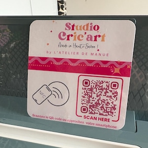 Peut inclure: Un autocollant blanc et rose avec le texte "Studio Cric'art" et "Made in Haute-Saône!". L'autocollant comporte également un code QR et les mots "SCAN HERE". Un symbole NFC est également présent.