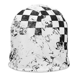 Op de afbeelding: Een witte beanie met een zwart-wit geblokt patroon aan de bovenkant en een gemarmerd ontwerp aan de onderkant. Een casual accessoire.