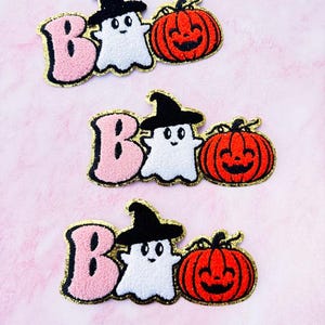 May include: Three embroidered iron-on patches featuring a ghost wearing a witch's hat, a pink letter "B", and a pumpkin. The patches are perfect for adding a spooky touch to clothing, bags, or other fabric items.