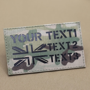 May include: A camouflage fabric patch with black stitching around the edges. The patch features a black Union Jack design and the text "YOUR TEXT1", "TEXT 2", and "TEXT 3".