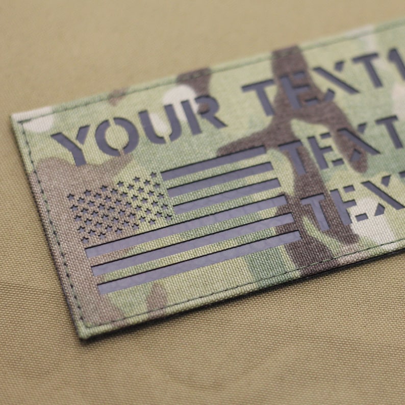 May include: A black and green camouflage fabric patch with a black American flag and the text "YOUR TEXT" printed on it.