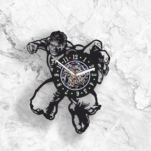 May include: Black and green vinyl wall clock featuring a silhouette of the Hulk character from Marvel Comics. The clock face has a blue and gold design with Roman numeral markings.