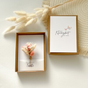 May include: A white card with the text "Du wirst Tante" and a small bouquet of dried flowers. The card is in a brown box. A second card with the text "Eine Kleinigkeit fur dich." and two butterflies is in a brown box.