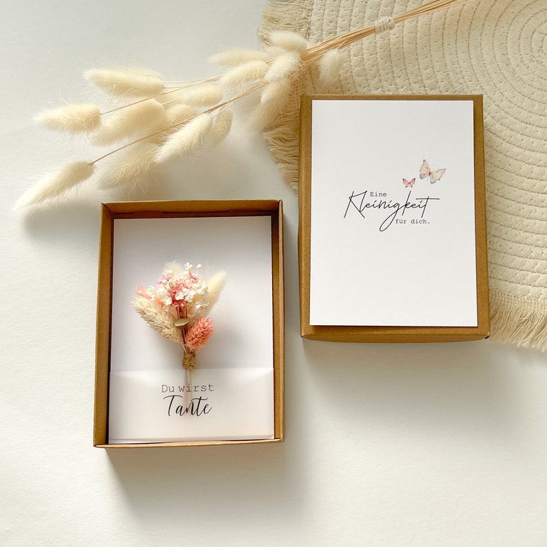 May include: A white card with the text "Du wirst Tante" and a small bouquet of dried flowers. The card is in a brown box. A second card with the text "Eine Kleinigkeit fur dich." and two butterflies is in a brown box.