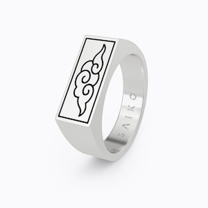 May include: A silver ring with a rectangular design featuring a black and white cloud graphic. The ring is engraved with the word "SAIKO" on the side.