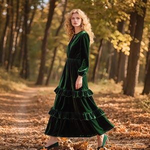 Könnte beinhalten: Ein langes, smaragdgrünes Samtkleid mit langen Ärmeln und einem gestuften, gerüschten Rock. Das Kleid hat ein figurbetontes Oberteil und einen fließenden Rock. Das Model trägt passende grüne Schuhe und geht auf einem Pfad in einem Wald.