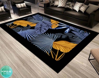 May include: A black area rug with a tropical leaf design. The rug features large blue and yellow leaves on a black background.