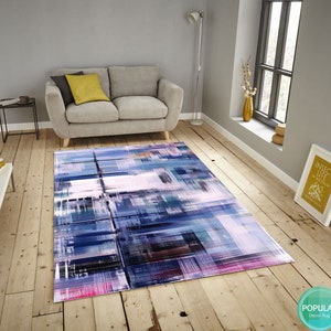 May include: Abstract geometric rug with shades of blue, pink, and gray. The rug has a modern design with a mix of colors and patterns.