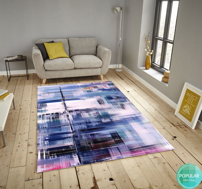 May include: Abstract geometric rug with shades of blue, pink, and gray. The rug has a modern design with a mix of colors and patterns.