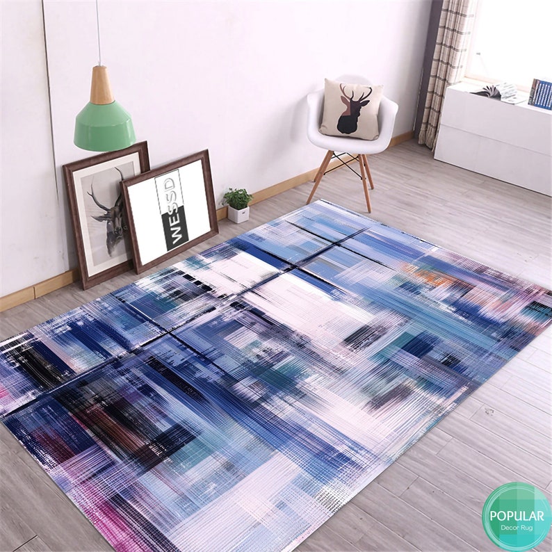 May include: Abstract area rug with a blue, white, and gray color scheme. The rug has a modern, geometric design with brushstrokes.