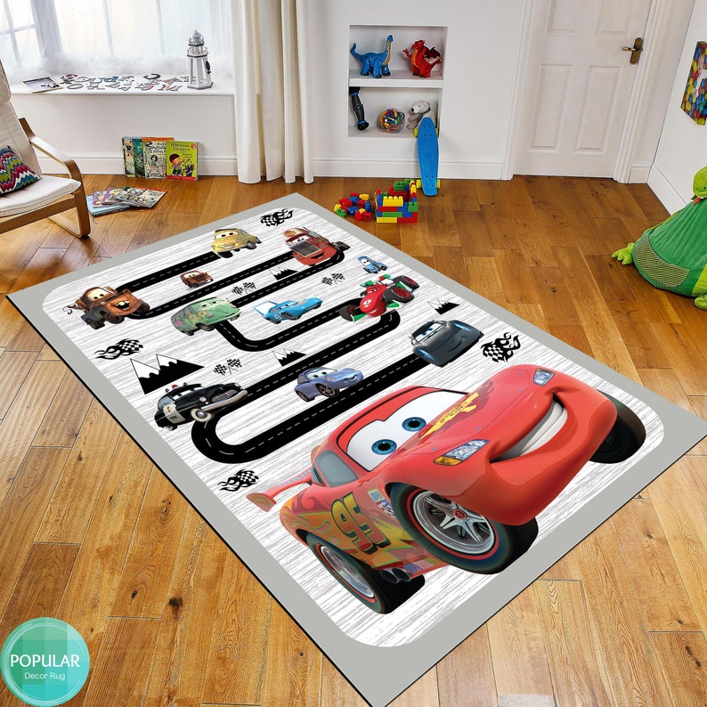 May include: A gray and white rug with a black race track design featuring cartoon cars, including Lightning McQueen. The rug is perfect for a child's room or play area.