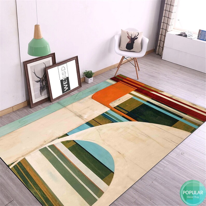 May include: Abstract geometric rug with stripes, circles, and squares in shades of green, blue, orange, and red on a cream background. The rug is on a wooden floor.