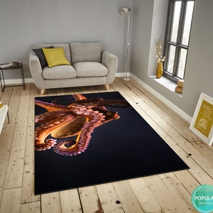 May include: A close-up of a rug featuring a large, orange octopus with pink tentacles against a dark blue background.