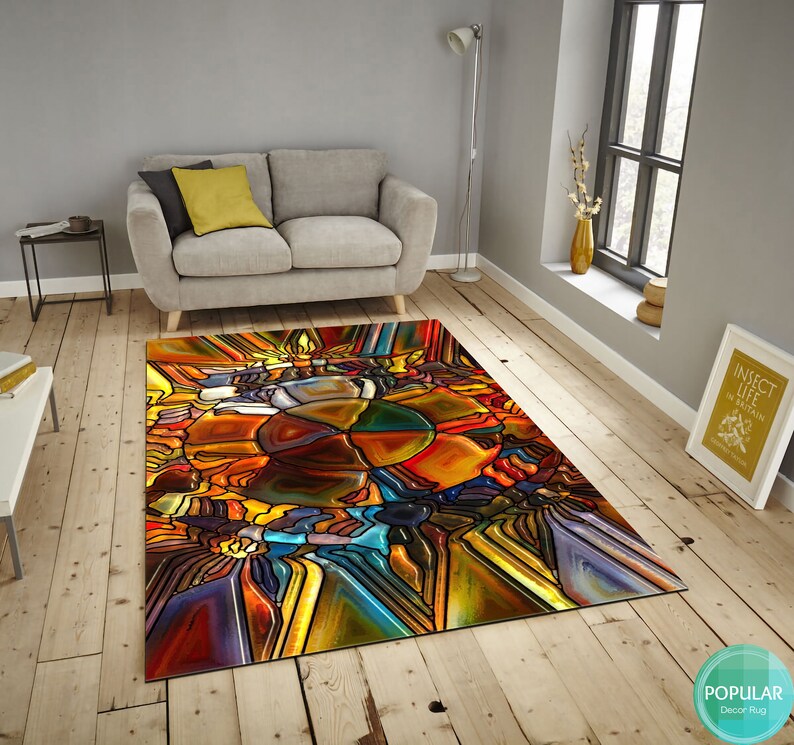 May include: Abstract stained glass style rug with a colorful design of yellow, orange, red, blue, green, and purple. The rug is on a wooden floor.