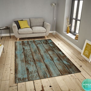 May include: A blue and brown distressed wood-look area rug with a rustic design. The rug is laid out on a hardwood floor in a living room setting.