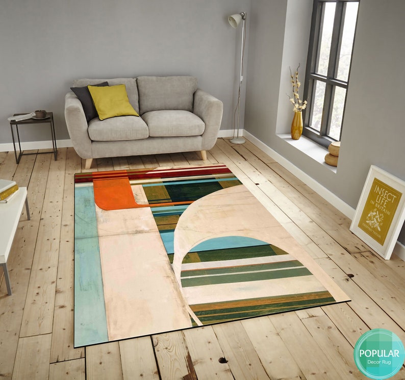 May include: Abstract geometric rug with a white background, orange, blue, green, and brown stripes. The rug has a modern design and would look great in a living room or bedroom.