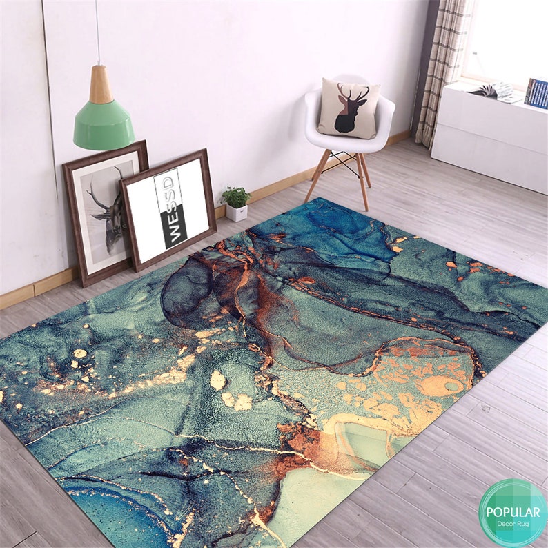 K&ouml;nnte beinhalten: Abstrakter Teppich mit einem blauen, gr&uuml;nen und goldenen Marmormuster. Der Teppich hat ein modernes und zeitgen&ouml;ssisches Design.