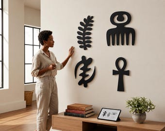 Puede incluir: Cuatro símbolos decorativos negros montados en la pared dispuestos en cuadrícula. Arriba a la izquierda una hoja tipo helecho, arriba a la derecha un icono en forma de peine, abajo a la izquierda una forma abstracta curva y abajo a la derecha un ankh.