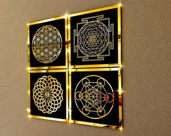 May include: A set of four square wall art panels featuring reflective gold geometric patterns on a black background. Each panel displays a distinct sacred geometry design, including the flower of life, a sri yantra, and other intricate circular motifs.