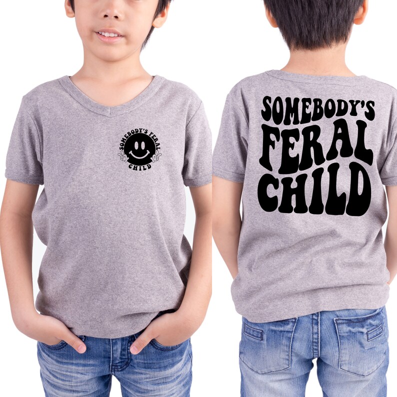 Może przedstawiać: Szara koszulka z dekoltem w kształcie litery V z uśmiechniętą buźką i napisem "Somebody's Feral Child" z przodu. Z tyłu koszulka ma napis "Somebody's Feral Child" w retro czcionce.