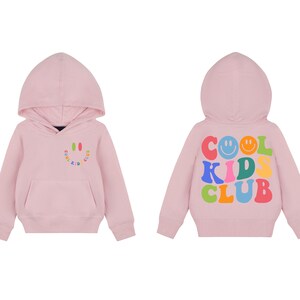 Peut inclure: Sweat-shirt &agrave; capuche rose avec un graphique de visage souriant sur le devant et le texte "COOL KIDS CLUB" avec des visages souriants au dos.