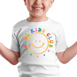 Peut inclure: T-shirt blanc avec un graphique color&eacute; "Cool Kids Club" repr&eacute;sentant un smiley jaune.