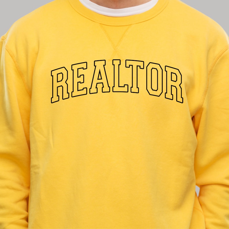 Peut inclure: Sweat-shirt jaune avec un texte noir qui dit "REALTOR" dans une police d'&eacute;criture universitaire.