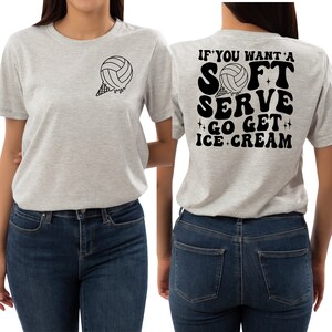 Puede incluir: Una camiseta gris con una pelota de voleibol en un cono de helado en la parte delantera y el texto "If you want a soft serve go get ice cream" en la parte posterior.