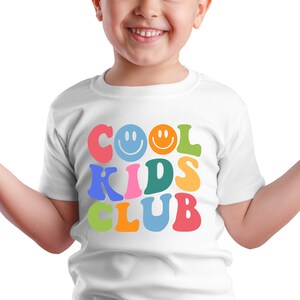 Peut inclure: T-shirt blanc avec un graphisme color&eacute; qui dit "COOL KIDS CLUB" avec des smileys.
