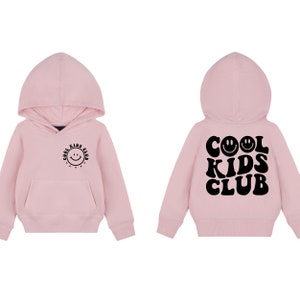 Peut inclure: Sweat-shirt &agrave; capuche rose avec un motif noir sur le devant qui dit "Cool Kids Club" avec un smiley et un motif noir au dos qui dit "Cool Kids Club" avec trois smileys.