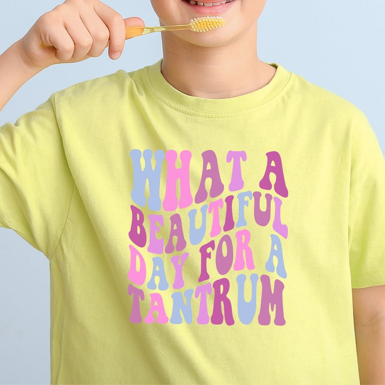May include: A yellow t-shirt with the text "WHAT A BEAUTIFUL DAY FOR A TANTRUM" in colorful, retro-style letters.