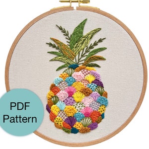May include: Embroidered pineapple pattern in a wooden embroidery hoop. The pineapple is filled with colorful flowers and leaves.