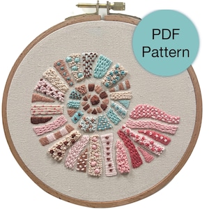 May include: An embroidered spiral design in a wooden hoop. The design features various textured stitches in shades of pink, brown, and teal. The text "PDF Pattern" is on a teal circle.