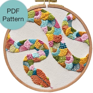 Peut inclure: Un motif de broderie coloré d'un serpent dans un cercle. Le serpent est composé de différentes formes et couleurs, notamment le rose, le jaune, le vert, le bleu et l'orange.