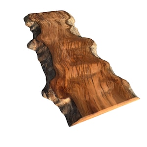 Könnte beinhalten: Eine Holzplatte mit natürlicher Kante, in warmbrauner Farbe mit ausgeprägten Maserungsmustern. Die unregelmäßigen Kanten unterstreichen die organische Form. Diese Platte, mit ihrer einzigartigen Form, eignet sich für verschiedene Holzbearbeitungsanwendungen. Die Länge beträgt ca. 100 cm.