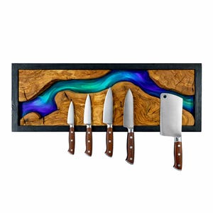 May include: A wooden knife holder with a black frame, featuring a river of blue and green resin. Six knives with brown handles are attached. The knives include a cleaver and various sizes of kitchen knives.