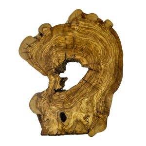 May include: A natural olive wood slab featuring a prominent organic shape with a central hollow void. The surface displays intricate, swirling grain patterns in shades of golden yellow, light brown, and dark brown, with visible knots and cracks.