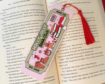 May include: A pink and green bookmark with a holly jolly book club theme. The bookmark features a ticket design with a red and white Santa hat, a gingerbread man, and a pair of boots. The bookmark also includes the text "Holly Jolly Book Club" and "Admit One".