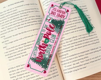 May include: Pink and green bookmark with a festive Christmas tree design. The bookmark has a ticket-style design with the text "Lifetime Admission to the North Pole Book Club" and "Holiday Elf Admit One".