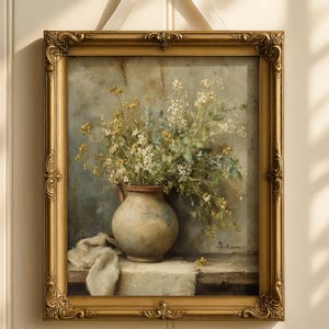May include: A framed floral still life painting. The artwork features a vase filled with white and yellow flowers. The painting is in a gold ornate frame and is suspended by a white ribbon tied in a bow.