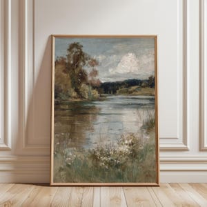 K&ouml;nnte beinhalten: Gerahmtes Landschaftsgem&auml;lde, das eine ruhige Seeszene darstellt. Das Kunstwerk weist eine ged&auml;mpfte Farbpalette mit Braun-, Gr&uuml;n- und Blaut&ouml;nen auf. Das Gem&auml;lde f&auml;ngt eine ruhige Wasserlandschaft mit B&auml;umen, Wolken und Reflexionen ein.