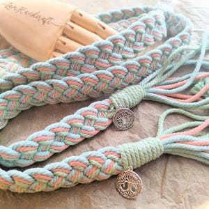 May include: Two braided cords with a light blue and pink color scheme. Each cord has a silver charm with a tree of life design.
