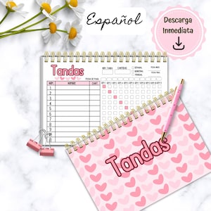 Pode incluir: Um caderno rosa e branco com um padrão de corações e a palavra "Tandas" em vermelho. O caderno tem uma espiral dourada e está aberto em uma página com uma tabela para controlar os pagamentos. A tabela tem colunas para o número, o nome, a quantidade, a data de pagamento e uma grade para marcar os pagamentos.