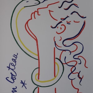 May include: A line art print featuring a profile of a head with a snake coiled around the neck. The artwork uses red, blue, green, and yellow lines on a white background. Text at the top reads EVE 60. 27, with Jean Cocteau signed on the side.