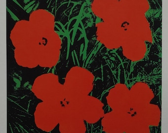 May include: A pop art print featuring five large red flowers against a black background with green foliage. The artwork, signed by Andy Warhol, has a bold, graphic style, with a vibrant color palette. The flowers are the focal point.