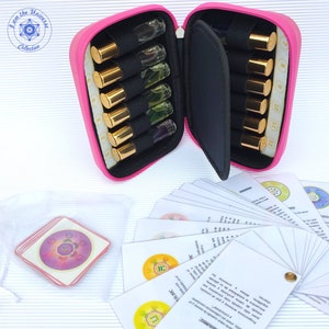 Può includere: Custodia rosa per il trasporto con un set di 12 piccoli flaconi di vetro con tappi dorati. La custodia è aperta e i flaconi sono visibili. C'è anche un set di carte con disegni circolari colorati e testo in un'altra lingua.