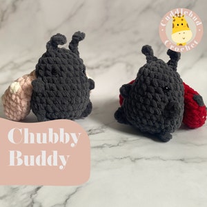 May include: Two crocheted plush toys, one black and one red, with the text "Chubby Buddy" in white on a pink background. The black toy has a pink and white crocheted toy attached to it. The red toy has a black crocheted toy attached to it. The toys are on a white marble surface. A logo for "Cuddlebud Crochet" is in the upper right corner of the image.