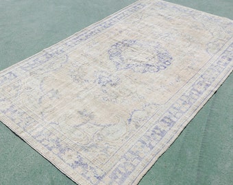 May include: A vintage rug with a light beige background and a blue floral pattern. The rug has a distressed look and a faded appearance.